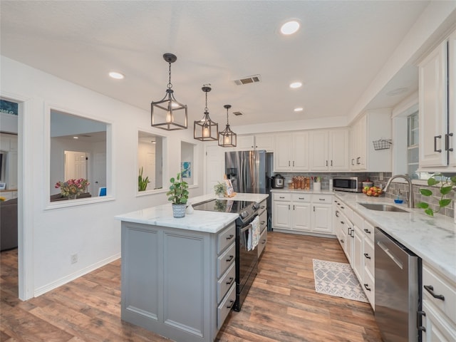 kitchen featuring appliances with stainless steel finishes, sink, hardwood / wood-style flooring, white cabinets, and a kitchen island