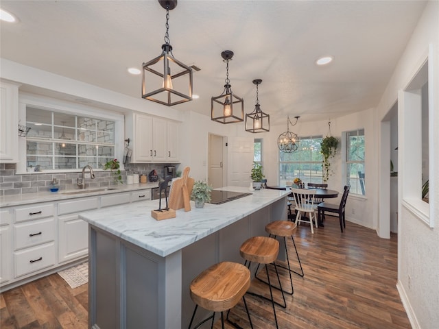 kitchen featuring dark hardwood / wood-style flooring, a center island, white cabinets, and sink