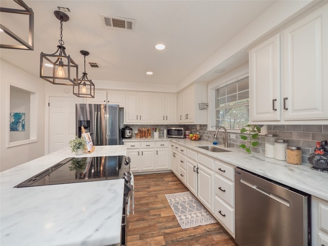 kitchen with white cabinets, sink, hanging light fixtures, dark hardwood / wood-style flooring, and stainless steel appliances