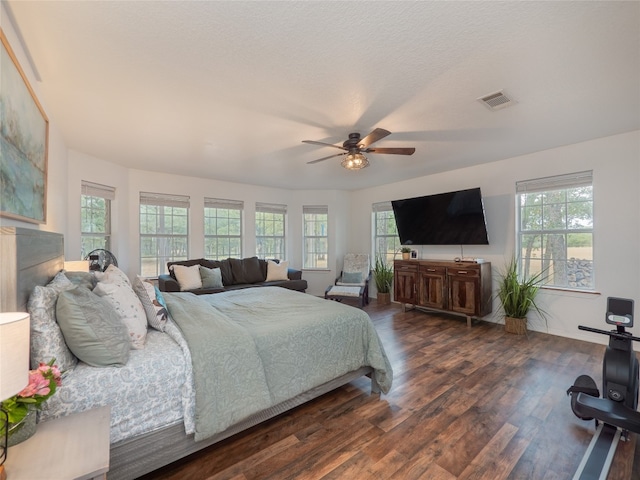 bedroom with ceiling fan, dark wood-type flooring, and multiple windows