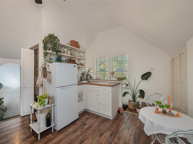 kitchen with white cabinetry, dark hardwood / wood-style flooring, white fridge, and high vaulted ceiling