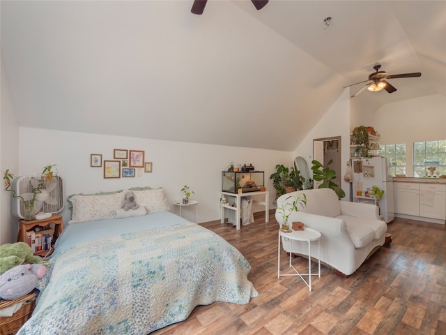 bedroom with ceiling fan, white fridge, dark wood-type flooring, and vaulted ceiling