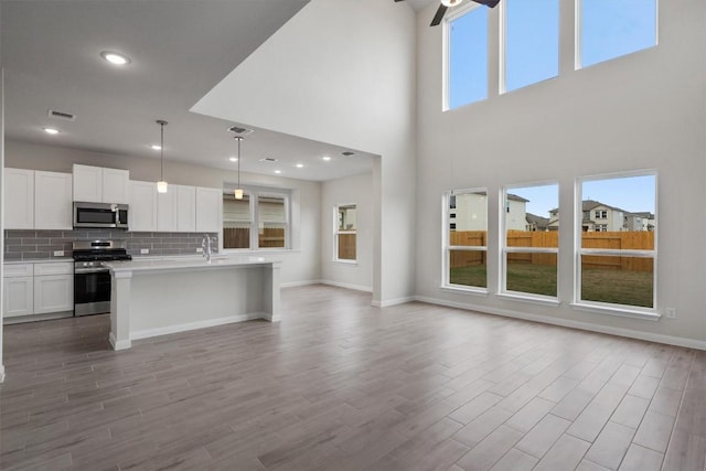 kitchen featuring white cabinetry, plenty of natural light, hanging light fixtures, and appliances with stainless steel finishes