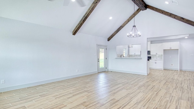 unfurnished living room featuring beamed ceiling, ceiling fan with notable chandelier, and high vaulted ceiling