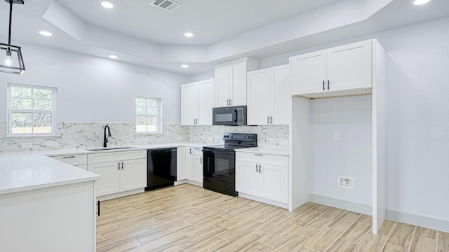 kitchen with sink, a healthy amount of sunlight, hanging light fixtures, white cabinets, and black appliances