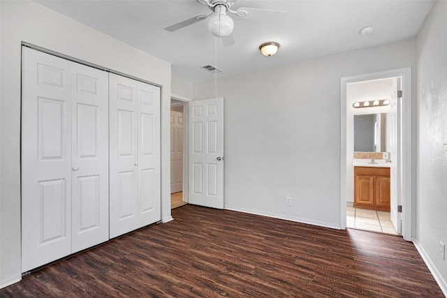 unfurnished bedroom featuring ceiling fan, ensuite bathroom, a closet, and dark hardwood / wood-style flooring