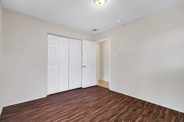 unfurnished bedroom featuring dark hardwood / wood-style floors and a closet