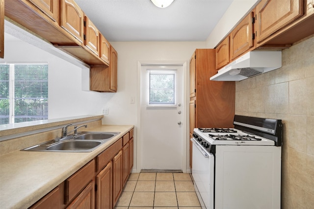 kitchen featuring white gas range, light tile patterned floors, tasteful backsplash, and sink