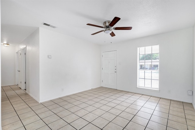 spare room with ceiling fan, a textured ceiling, and light tile patterned flooring