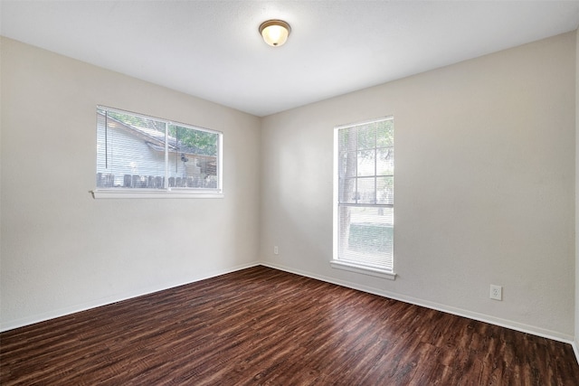 spare room featuring dark hardwood / wood-style floors and a healthy amount of sunlight