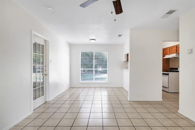 tiled empty room with ceiling fan and a wealth of natural light