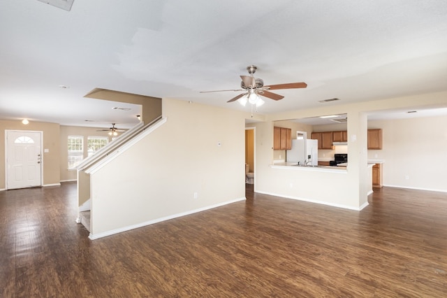 unfurnished living room featuring dark wood-type flooring and ceiling fan