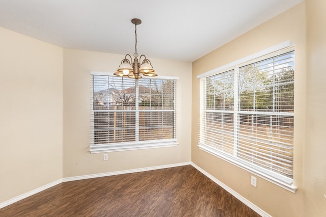 unfurnished dining area featuring hardwood / wood-style flooring, a healthy amount of sunlight, and a notable chandelier