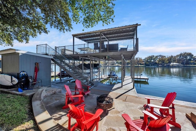 view of dock with a patio area, a deck with water view, and an outdoor fire pit