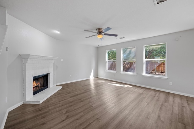 unfurnished living room with dark wood-type flooring, a fireplace, and ceiling fan