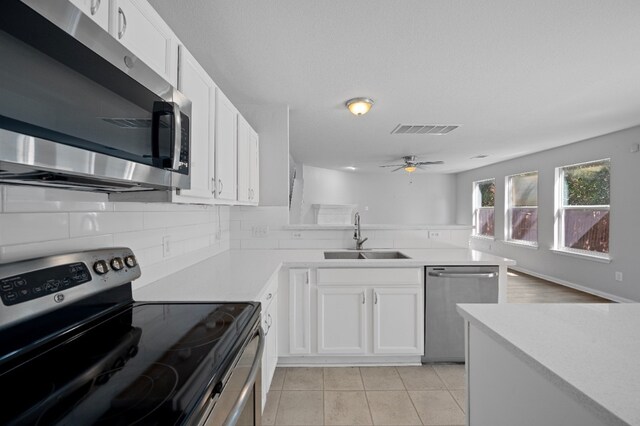 kitchen featuring light tile patterned flooring, white cabinets, stainless steel appliances, and sink