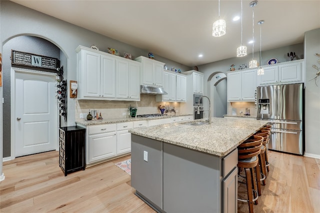 kitchen with stainless steel appliances, a kitchen island with sink, and white cabinets