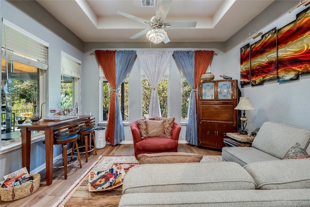 sitting room with a raised ceiling, light hardwood / wood-style floors, and ceiling fan