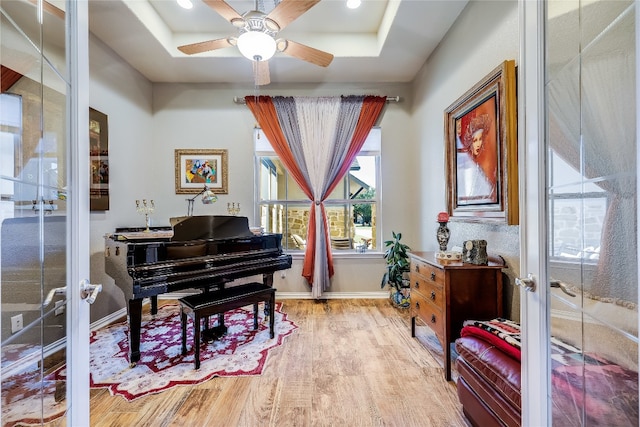 misc room featuring light hardwood / wood-style flooring, french doors, ceiling fan, and a raised ceiling