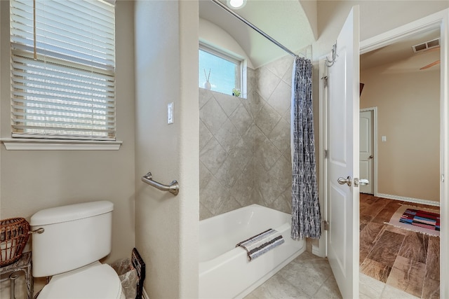 bathroom featuring toilet and shower / tub combo with curtain