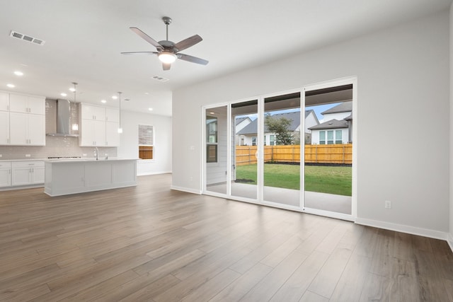 unfurnished living room featuring hardwood / wood-style floors, sink, and ceiling fan