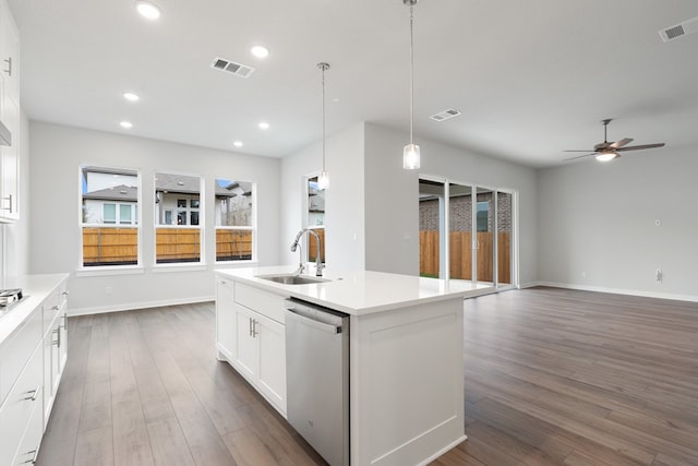 kitchen with sink, dark hardwood / wood-style flooring, stainless steel dishwasher, white cabinets, and a kitchen island with sink