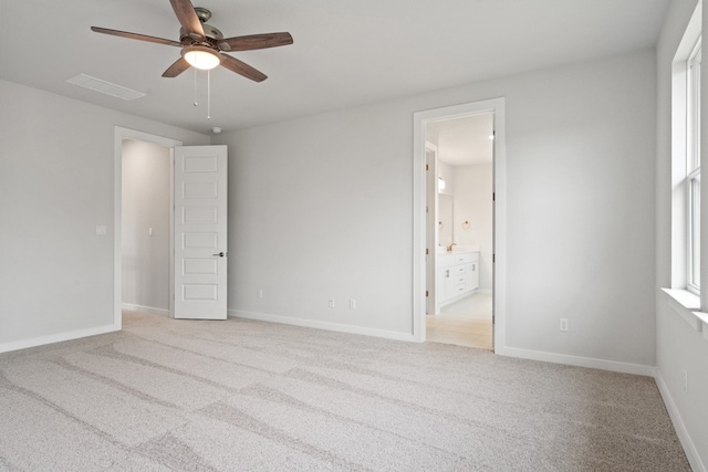 unfurnished bedroom featuring light carpet, ensuite bathroom, and ceiling fan