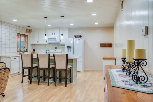 kitchen with decorative backsplash, white cabinetry, light wood-type flooring, pendant lighting, and white appliances