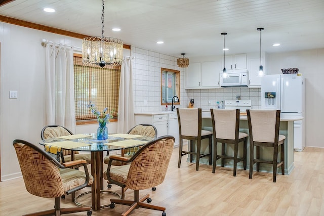 dining area with sink, an inviting chandelier, and light wood-type flooring