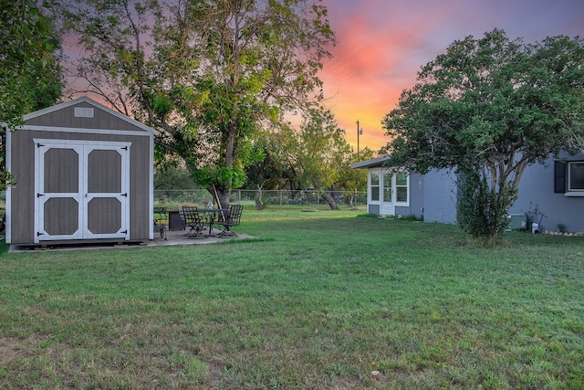 yard at dusk featuring a patio and a storage unit