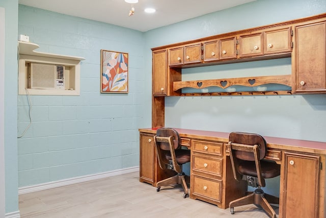 home office featuring a wall unit AC, light hardwood / wood-style flooring, and built in desk