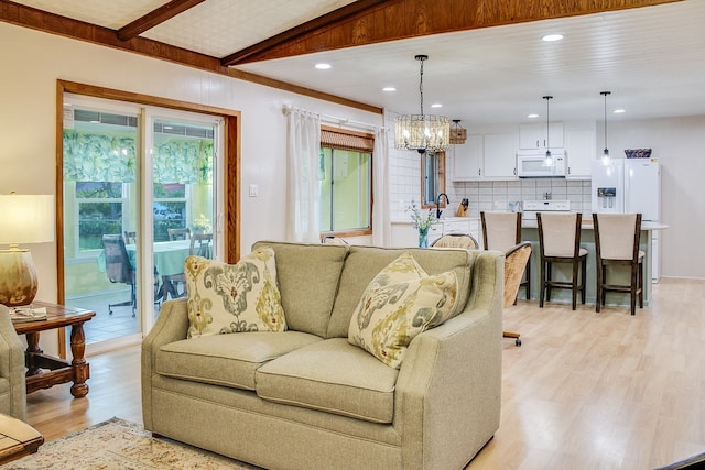 living room with sink, light hardwood / wood-style floors, and an inviting chandelier