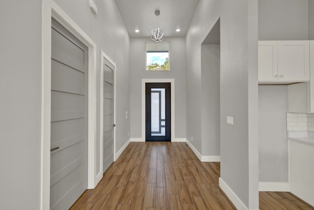 entryway with an inviting chandelier, a high ceiling, and light wood-type flooring