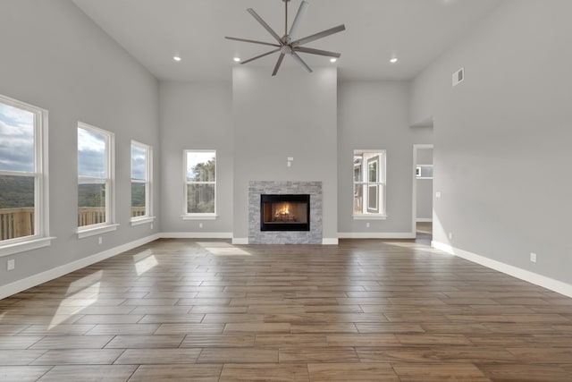 unfurnished living room with a fireplace, dark hardwood / wood-style floors, a high ceiling, and ceiling fan