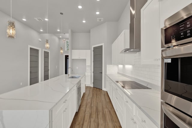 kitchen with sink, light stone counters, decorative light fixtures, and white cabinets