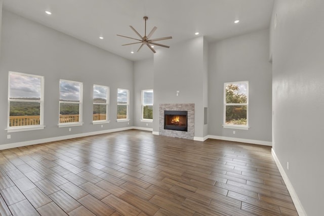 unfurnished living room featuring a healthy amount of sunlight, wood-type flooring, and a high ceiling