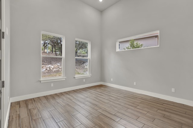 unfurnished room with light hardwood / wood-style floors and a towering ceiling