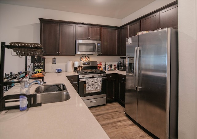 kitchen featuring appliances with stainless steel finishes, light hardwood / wood-style flooring, dark brown cabinetry, and sink