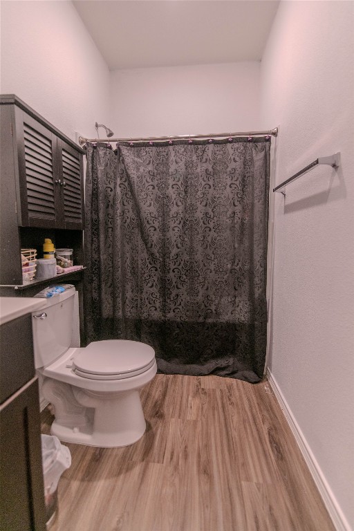 bathroom with toilet, curtained shower, hardwood / wood-style flooring, and vanity