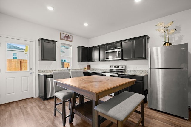 kitchen featuring light stone countertops, stainless steel appliances, and light wood-type flooring