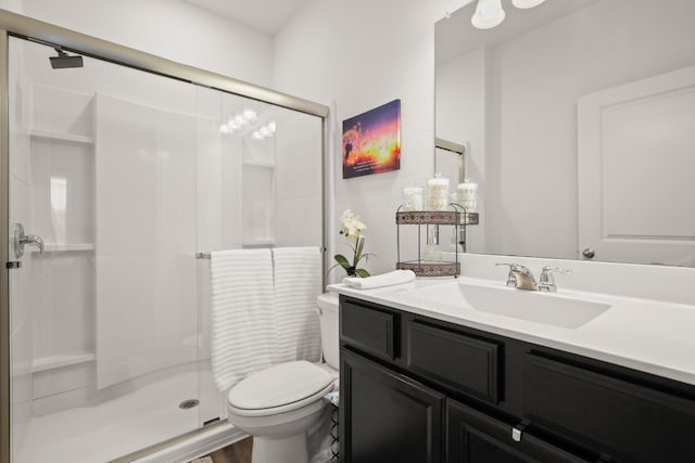 bathroom featuring toilet, hardwood / wood-style flooring, a shower with shower door, and vanity