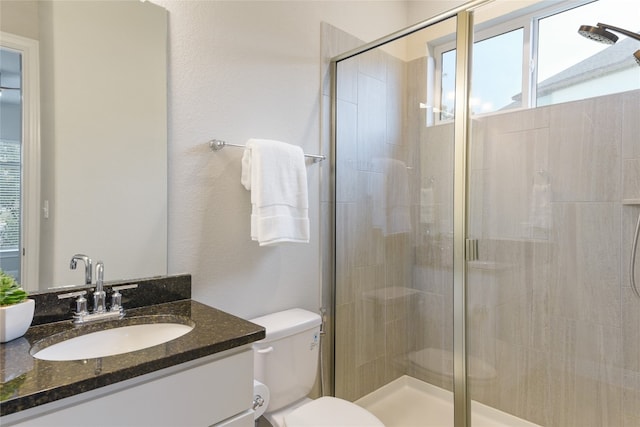 bathroom with toilet, a shower with shower door, and vanity