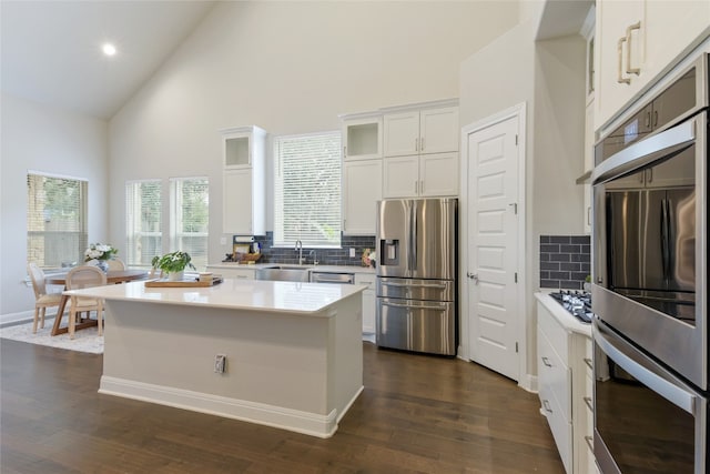 kitchen with white cabinets, stainless steel appliances, dark wood-type flooring, and a kitchen island