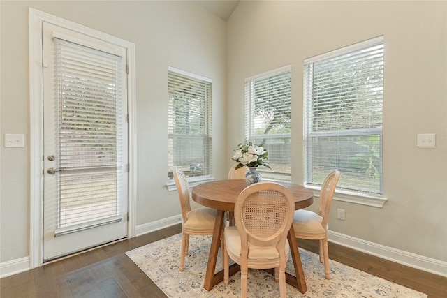 dining area featuring lofted ceiling and dark hardwood / wood-style flooring