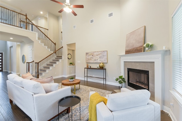 living room featuring a wealth of natural light, a high ceiling, a fireplace, and dark hardwood / wood-style floors