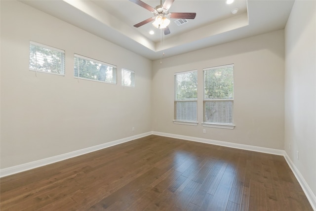 unfurnished room featuring ceiling fan, a tray ceiling, and dark hardwood / wood-style flooring