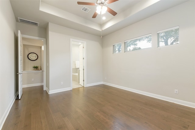 unfurnished room featuring dark wood-type flooring, a tray ceiling, and ceiling fan