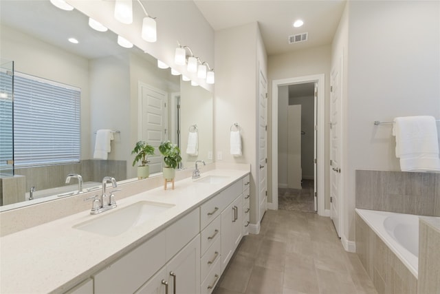 bathroom with vanity, a relaxing tiled tub, and tile patterned flooring