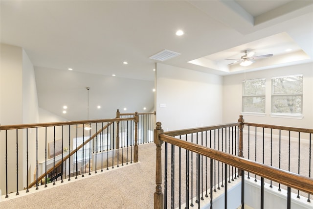 hall with carpet flooring and a raised ceiling