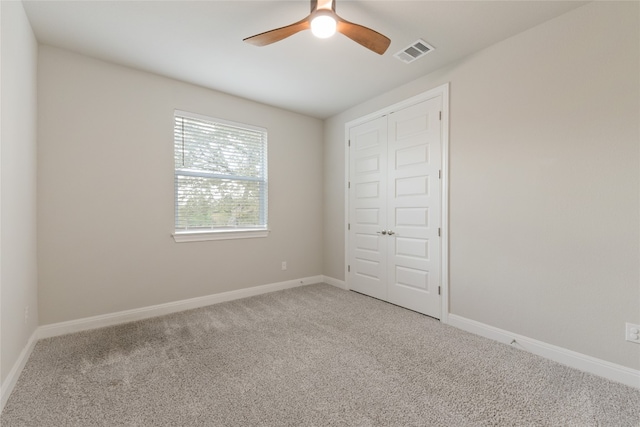 unfurnished bedroom featuring a closet, light colored carpet, and ceiling fan